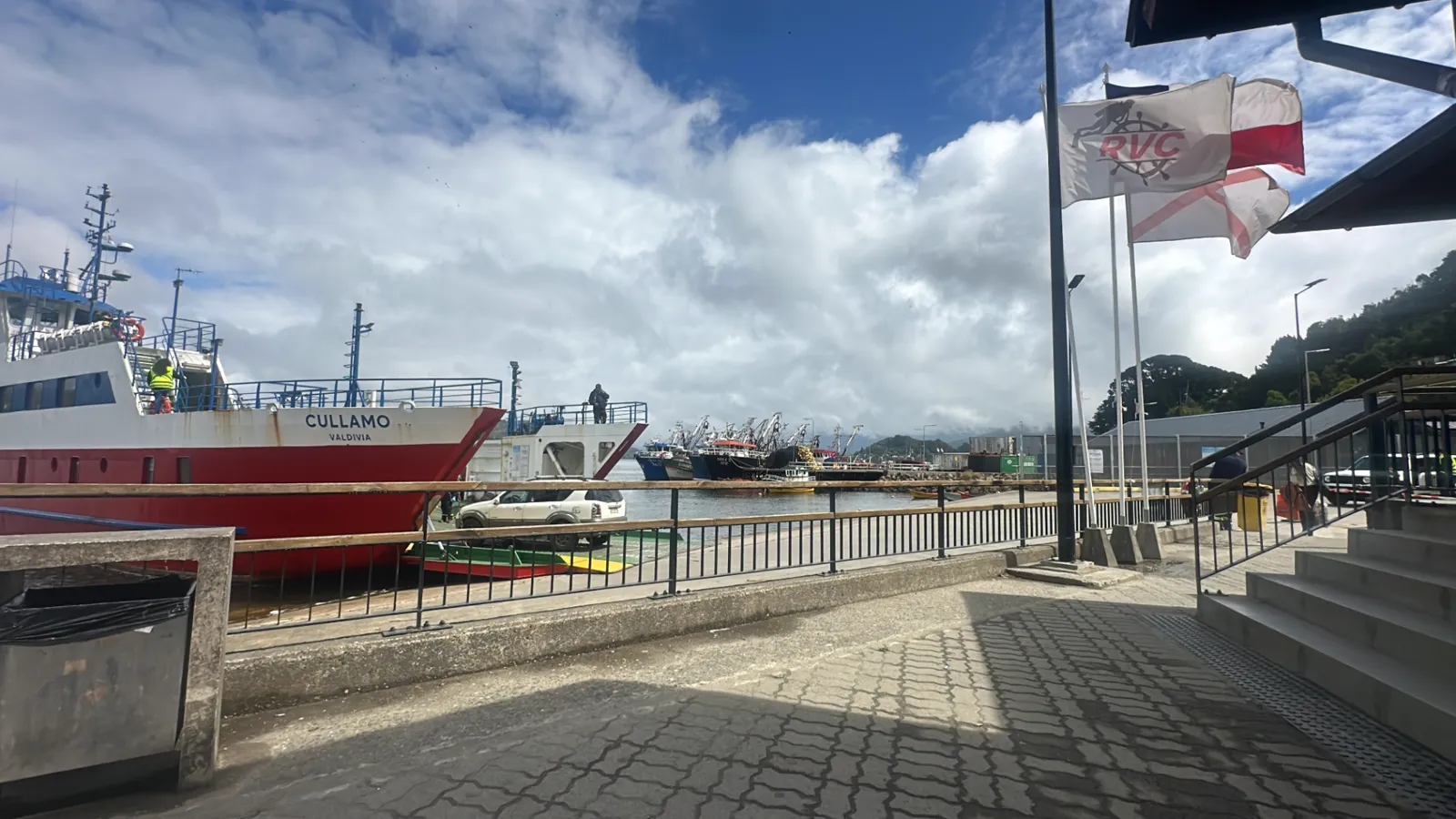 La Cullamó atracada en el muelle, con un vehículo en la rampa y las banderas de RVC al lado
